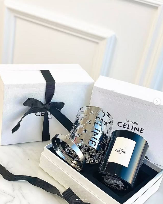 Celine Haute Parfumerie Silence Blanc scented candle gift set. The set features a 240g perfumed candle housed in a black glass container with a black wax wick. It includes a metallic cut-out candle holder designed to mimic the lines of a Celine perfume bo - Other Brand Candles | Aleppo Gift UAE